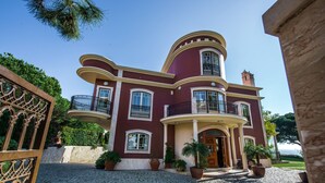 Un edificio grande de dos pisos con fachada curva, varios balcones y un camino de adoquines.
