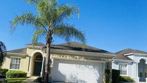 A residential house with a garage, a driveway, and a palm tree.