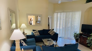 A living room with a sofa set, a coffee table, a TV, and a ceiling fan.