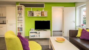 Ein modernes Wohnzimmer mit Flachbildfernseher, Bücherregal, Sofa und Couchtisch.