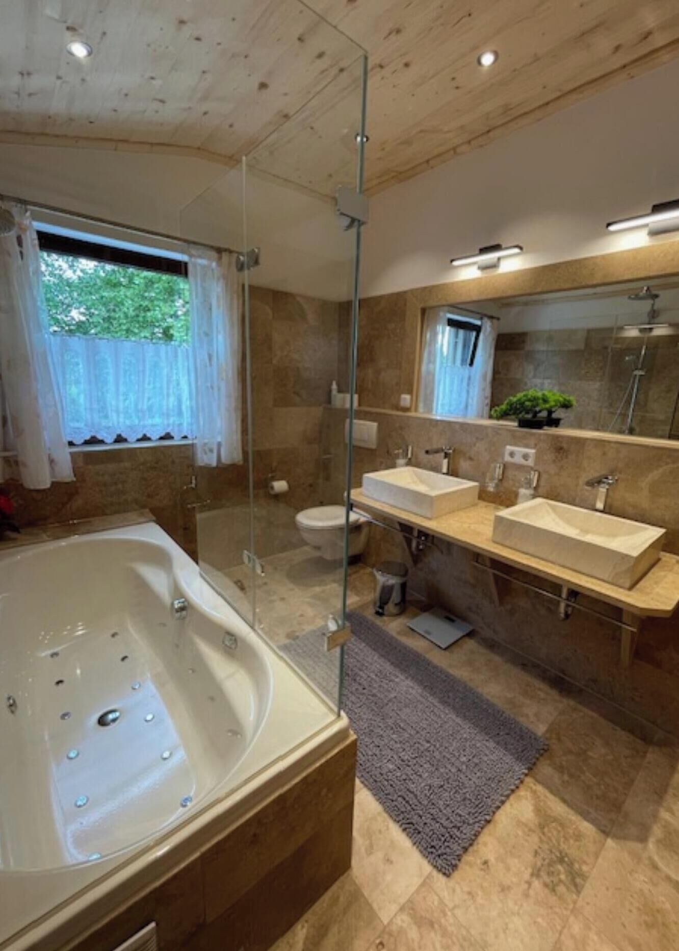 A modern bathroom with a glass-enclosed shower, a freestanding bathtub, and two sinks.