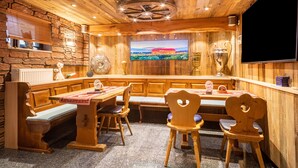 A wooden interior with a stone wall, wooden furniture, a television, and a trophy. - Apartment "Zur Imme" with Mountain View, Wi-Fi and Air Conditioning (Lindau)