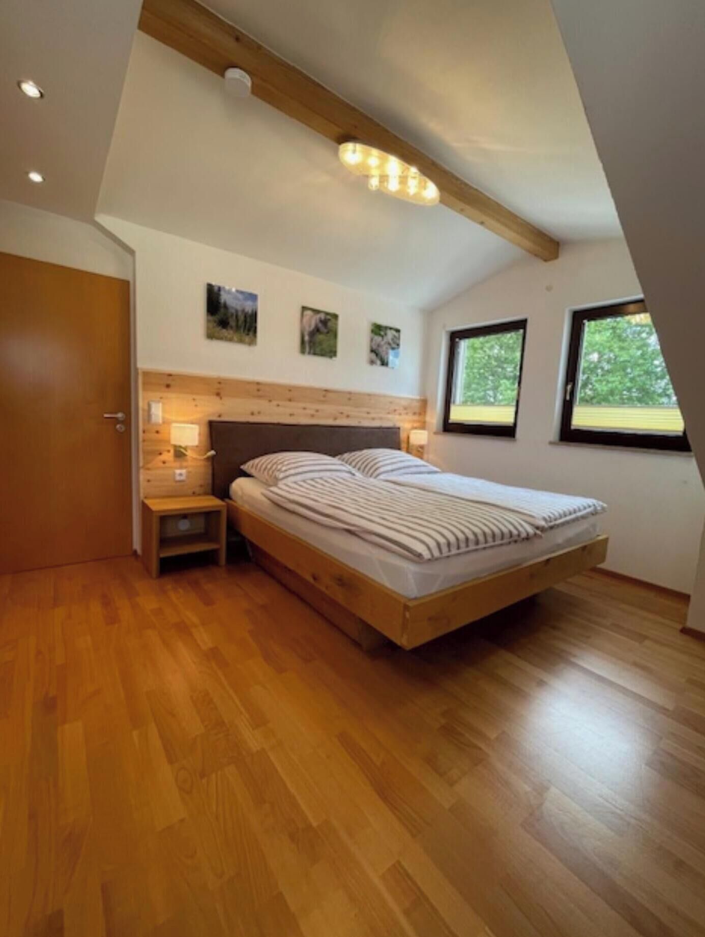 Ein Schlafzimmer mit einem hölzernen Bett, einem Nachttisch, einer Wandleuchte und einer Deckenlampe.
