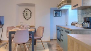 Une cuisine moderne avec des meubles en bois, une machine à café et un coin repas comprenant une table et des chaises.
