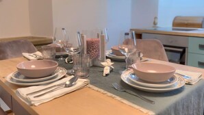 Une table à manger dressée avec des assiettes, des bols, des verres et des couverts.