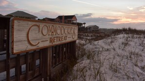 A wooden sign with the text "Commodore's Retreat" in a rustic style, set against a backdrop of a sandy landscape with a few buildings in the distance. - Right on the Beach - Pool - 1BR 1BA - King & Bunks (Santa Rosa Beach)
