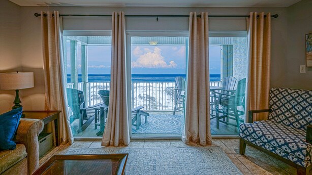 A room with a view of the ocean, a balcony with chairs, and a patterned sofa. - Right on the Beach - Pool - 1BR 1BA - King & Bunks (Santa Rosa Beach)