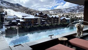 A pool area with a view of a snow-covered mountain and a lodge. - Ski-in/out, Best Views, Best Location at Snowmass Base Village | One Snowmass (Snowmass Village)