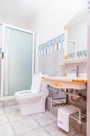 A bathroom with a toilet, sink, and towel rack. - Marahaba Apartment Hotel (Kampala)