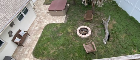 Een achtertuin met een vuurkuil, tuinmeubilair en een palmboom.