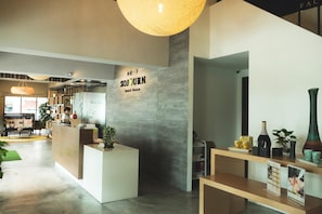 A reception area with a sign for 'SOJOURN Guest House,' a reception desk, and a counter with various items. - Sojourn Guest House (Ampang)