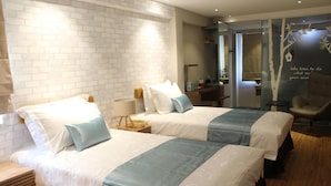 Quarto de hotel com duas camas, uma mesa de cabeceira de madeira, uma escrivaninha e uma cadeira.