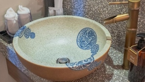 Uma pia de banheiro com cuba redonda, torneira e dispenser de sabonete líquido.