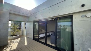 Una camera d'hotel moderna con un'ampia porta scorrevole in vetro, una pianta in vaso e vista sulla città.