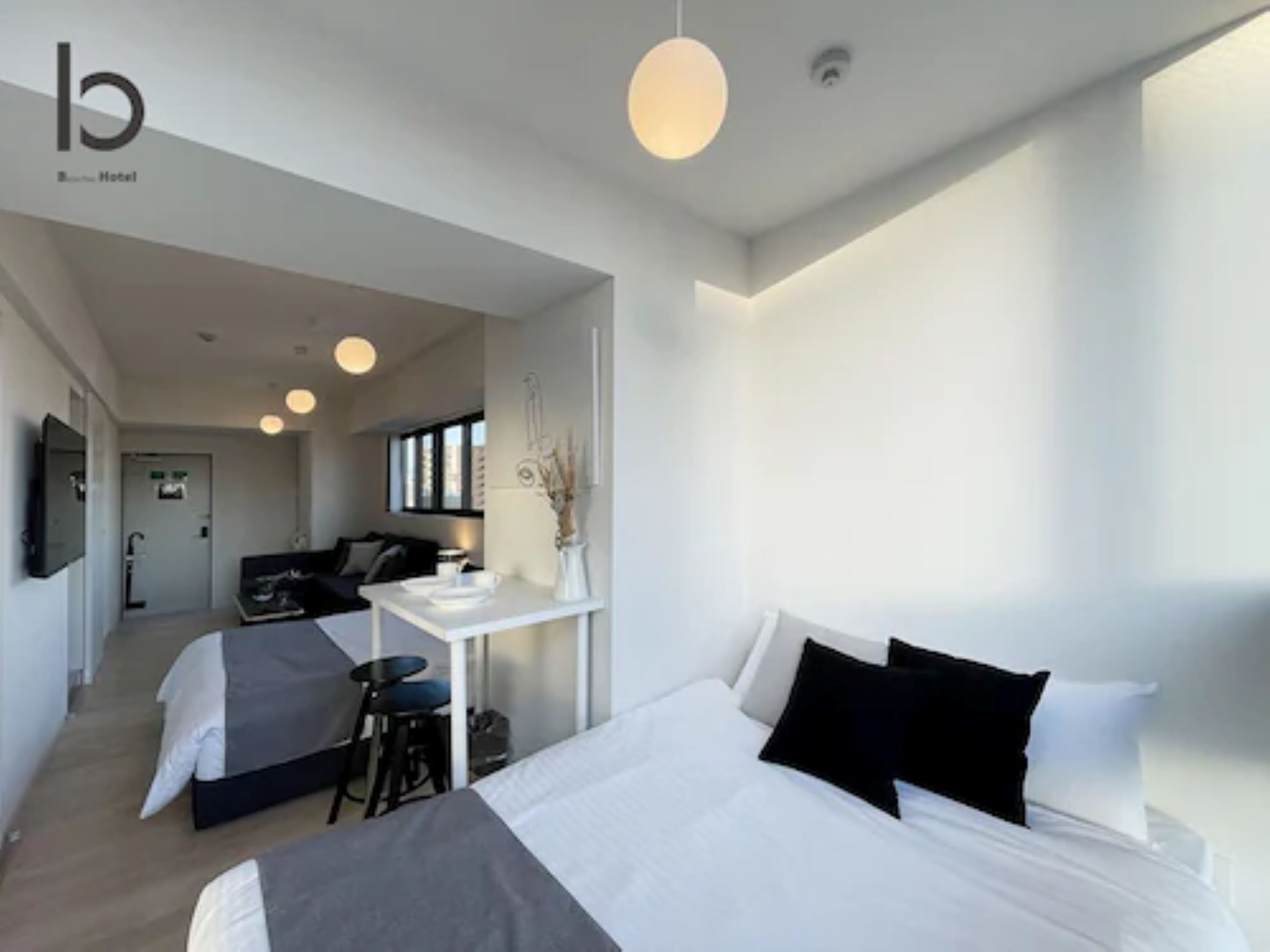 Moderni hotellihuone, jossa on suuri sänky, pieni työpöytä ja oleskelualue.