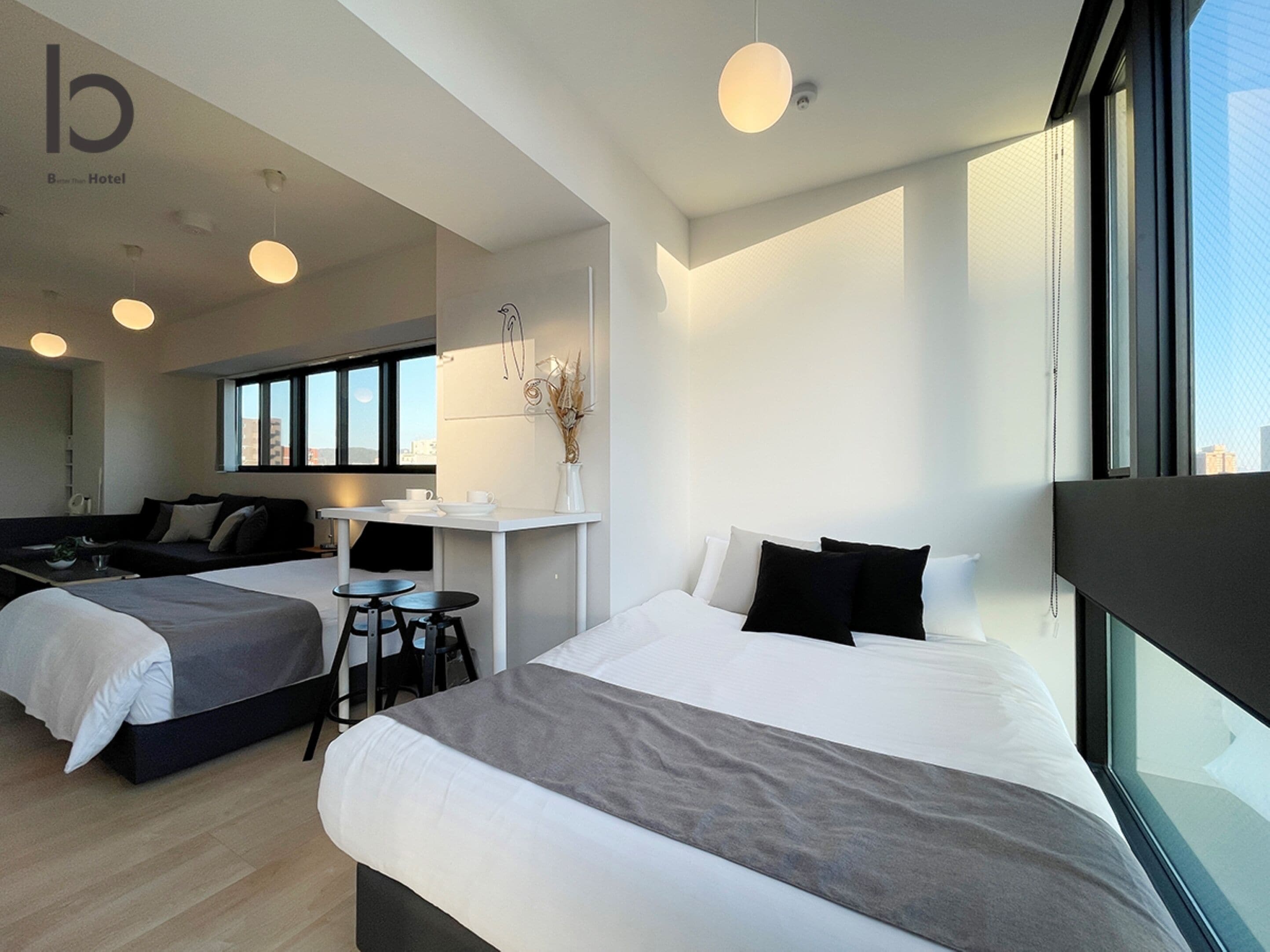 A modern hotel room with two beds, a small desk, and a large window.