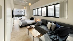 Una camera d'albergo moderna con un letto grande, un divano, un tavolino e una TV.