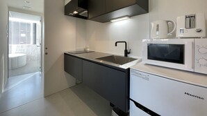 Una cucina moderna con forno a microonde integrato, lavello e frigorifero compatto.