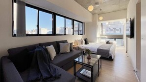 Una camera d'albergo moderna con un divano, un letto, un tavolino e una televisione.