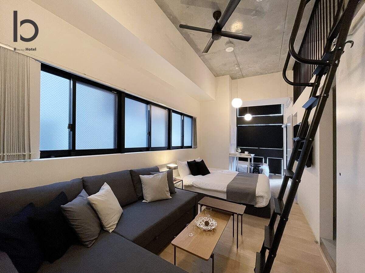 Une chambre d’hôtel moderne équipée d’un canapé, d’un lit, d’une table à manger et d’un escalier.