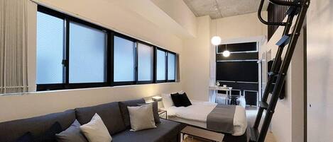 Une chambre d’hôtel moderne équipée d’un canapé, d’un lit, d’une table à manger et d’un escalier.