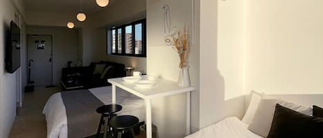 A modern hotel room with a large bed, a small desk, and a view of the city.