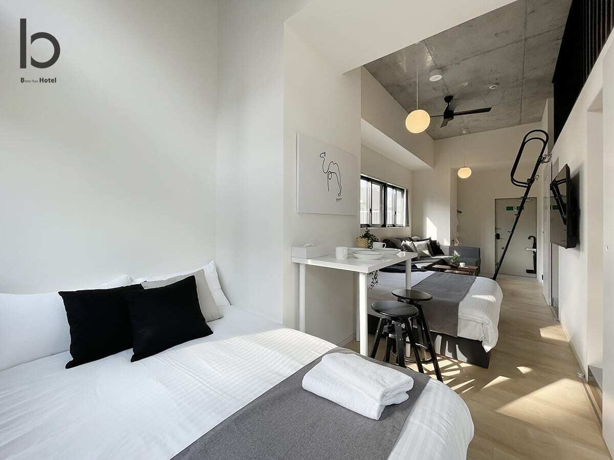 A modern hotel room with a bed, a desk, and a kitchenette.