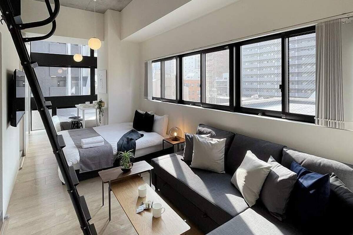 Ein modernes Hotelzimmer mit Schlafkoje, einer Couch, einem Couchtisch und einem großen Fenster mit Blick auf die Stadt.