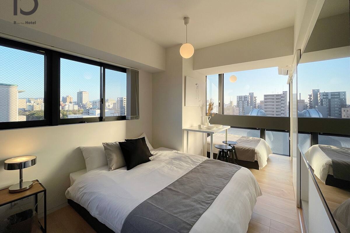 Ein modernes Hotelzimmer mit einem großen Bett, einem Schreibtisch und einem Balkon mit Blick auf die Stadt.