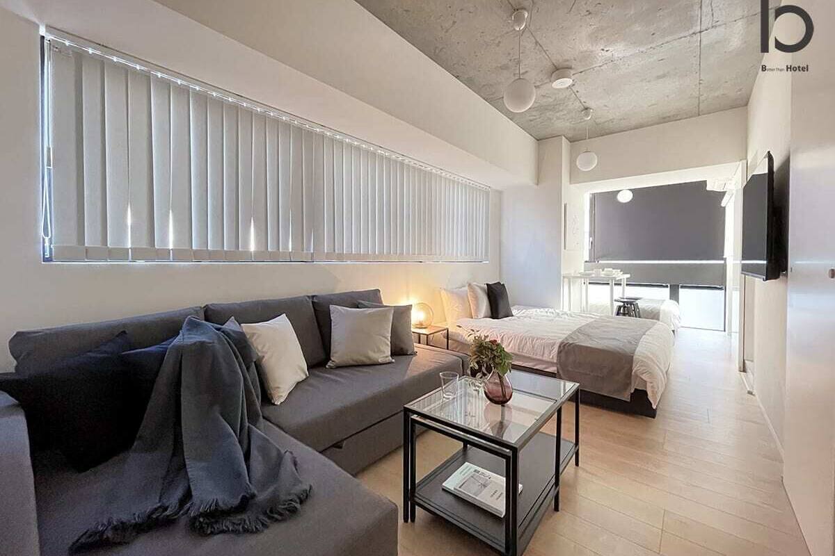 Ein modernes Hotelzimmer mit einer Couch, einem Glastisch, einem Bett und einem an der Wand befestigten Fernseher.