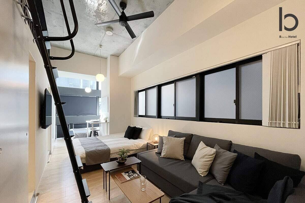 Ein modernes Hotelzimmer mit einer Couch, einem Couchtisch und einem an der Wand montierten Fernseher.