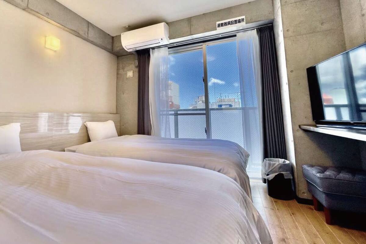 Habitación de hotel con cama, televisión, aire acondicionado y ventana con vista.