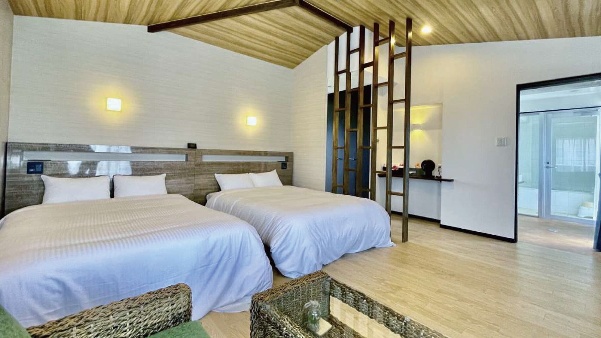 Een hotelkamer met twee bedden, een houten plafond en uitzicht op de badkamer.