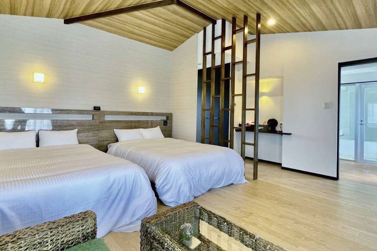 Habitación de hotel con dos camas, techo de madera y vista al baño.