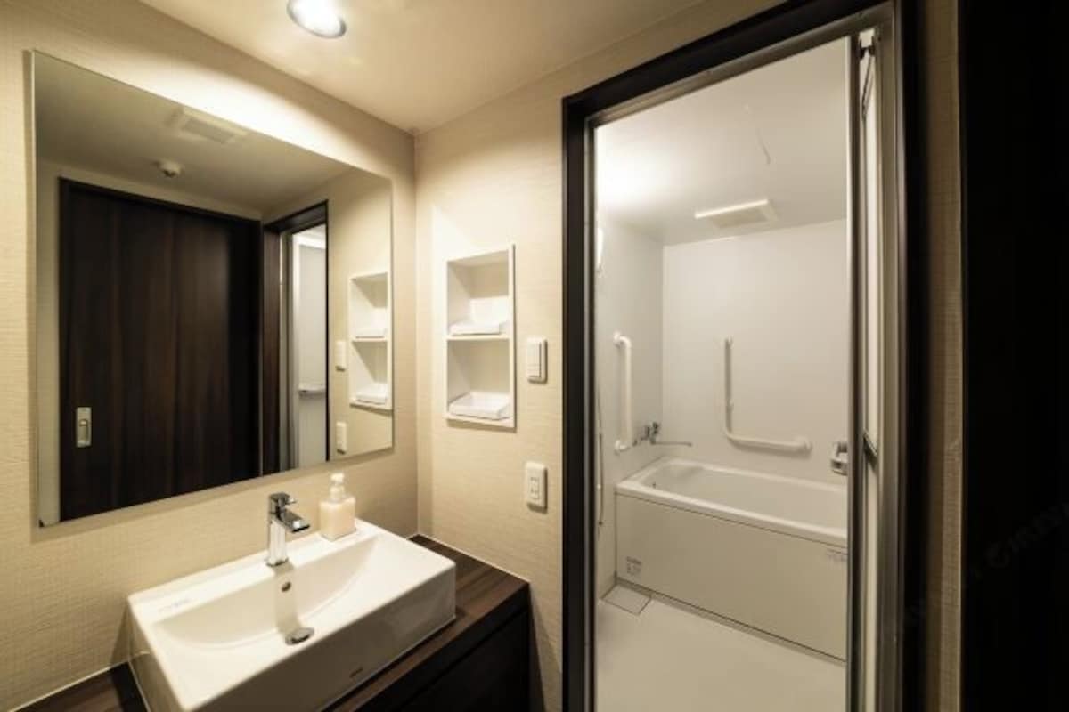 A modern bathroom with a large mirror, a sink, and a walk-in shower.