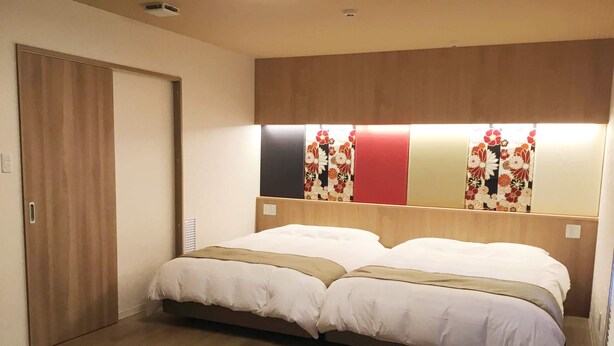 A hotel room with a double bed, a wooden headboard, and a sliding door. - Kyoto Central Inn (Kyoto)