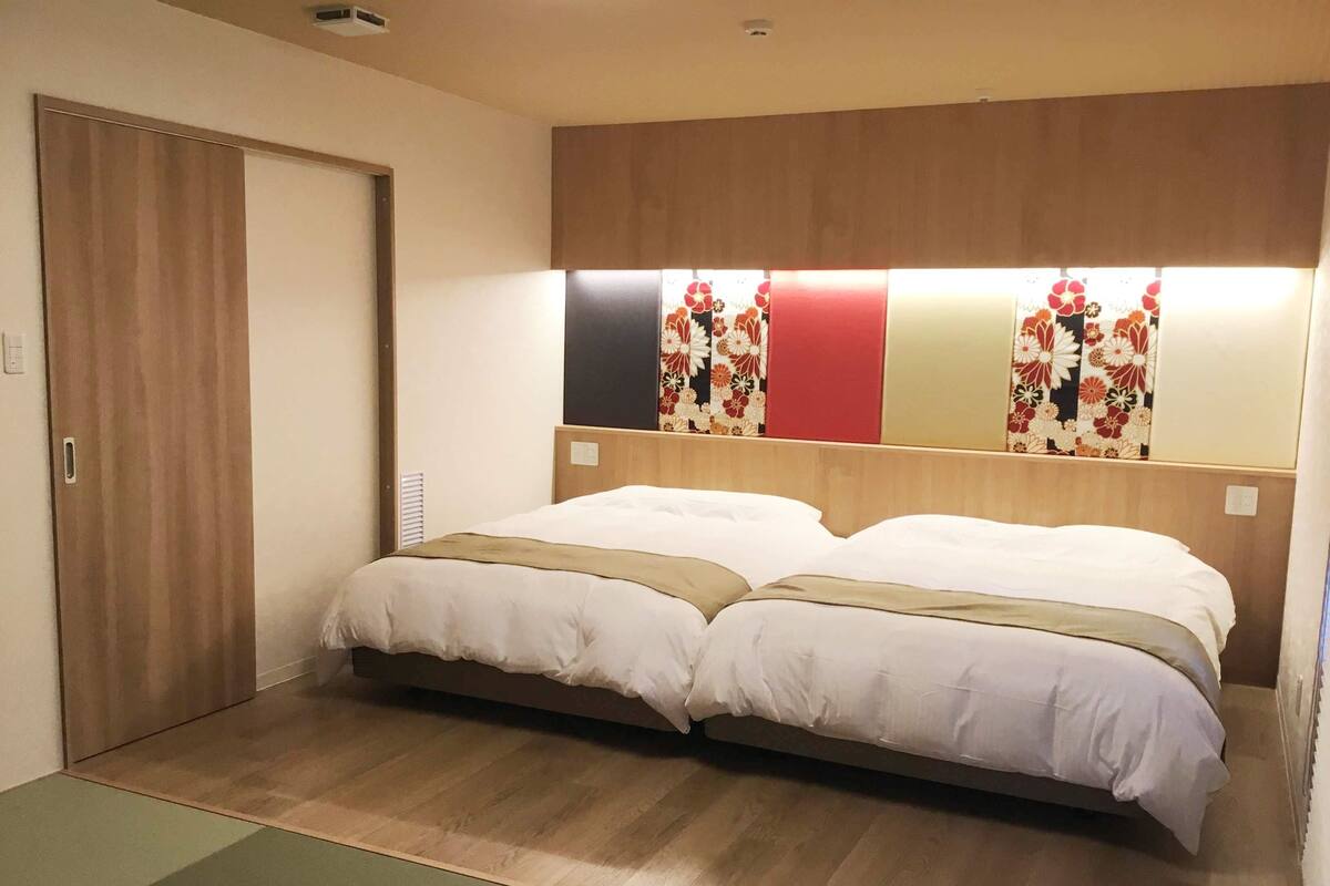 Ein Hotelzimmer mit Doppelbett, Holz-Kopfteil und einer Schiebetür.