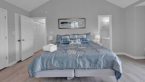 Une chambre à coucher avec un grand lit, un ventilateur de plafond et un tableau encadré au mur.