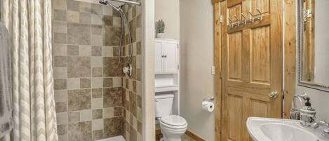 A bathroom with a shower, toilet, and sink.