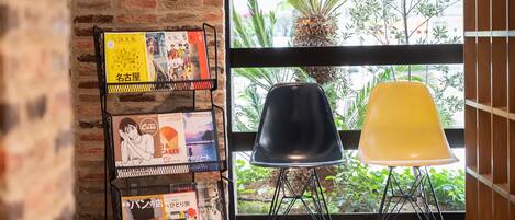 A room with a brick wall, a window with a view of greenery, and a black and yellow chair.