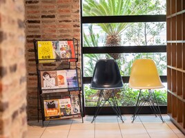A room with a brick wall, a window with a view of greenery, and a black and yellow chair.