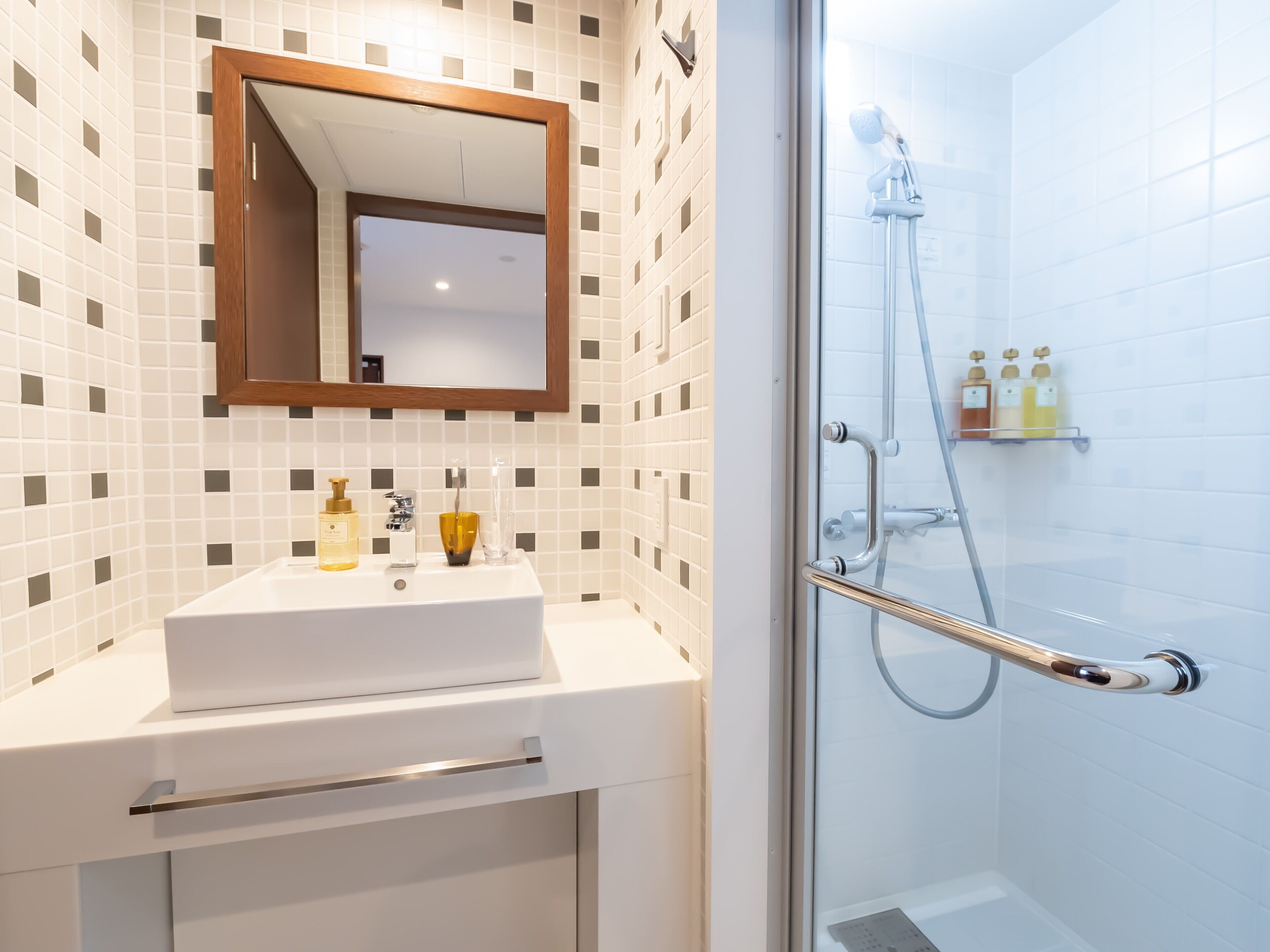 A modern bathroom with a white sink, mirror, and shower.