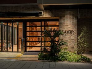 Entrada de un hotel con fachada de ladrillo, un cartel que indica acceso al Hotel Loisir y una puerta de cristal que da a la construcción.