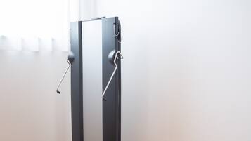 A piece of exercise equipment with a handle and a foot pedal, placed on a wooden floor against a white wall.