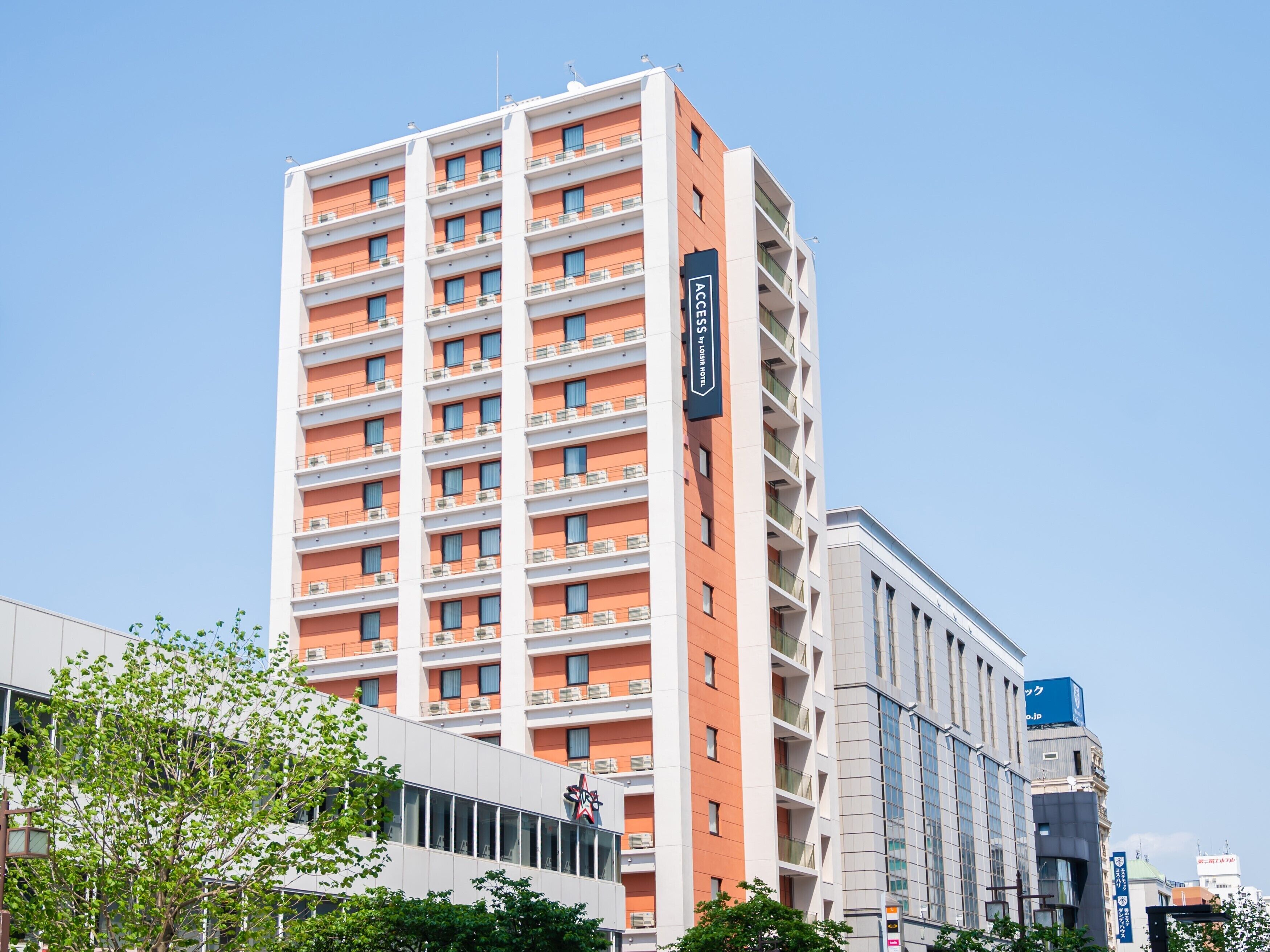 A multi-story hotel with a modern design, featuring balconies on each floor and a prominent sign indicating it is an ACCENT hotel.