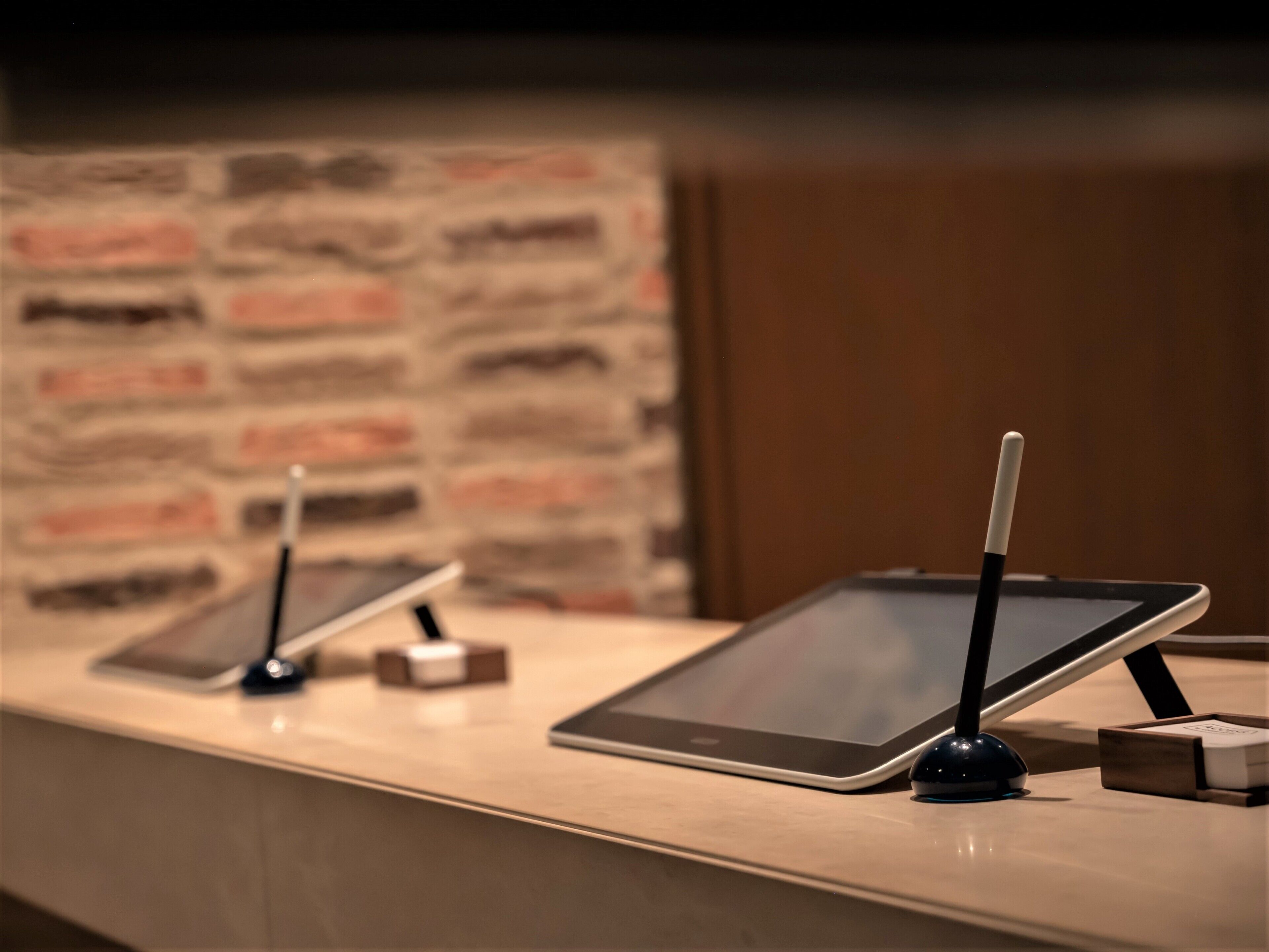 Una recepción con dos tabletas sobre soportes, un bolígrafo y una caja pequeña.