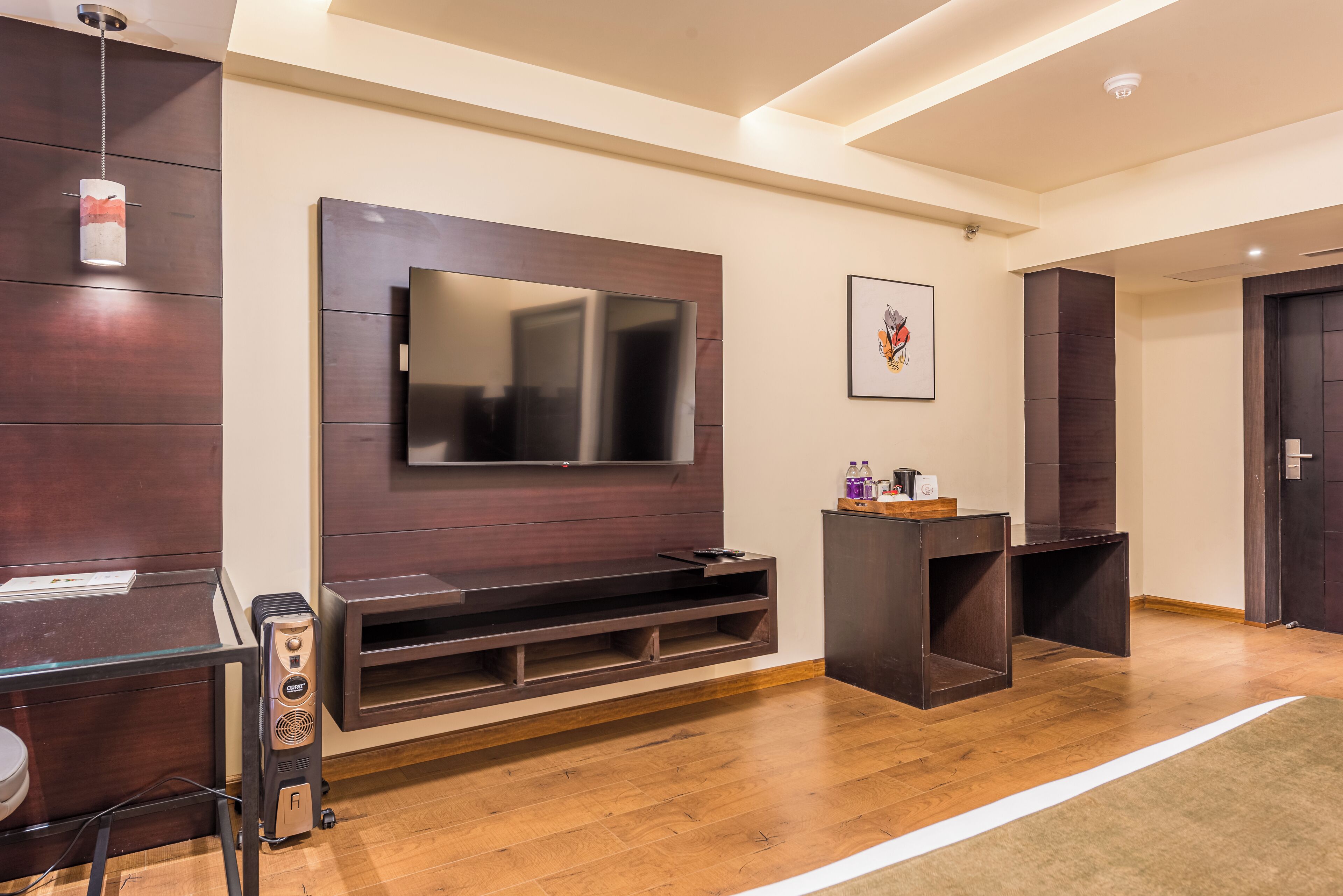 Una sala de estar moderna con un televisor de pantalla plana grande montado en una pared de madera, una mesa de centro de vidrio y un mueble de madera oscura.