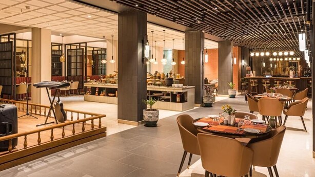 A spacious hotel lobby with multiple dining areas, a stage, and a bar. - Udaan Himalayan Suites and Spa (Darjeeling)