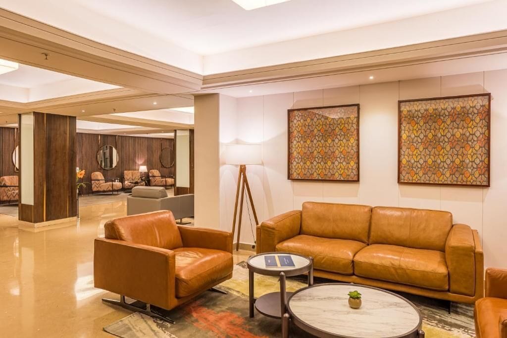 A modern hotel lobby with leather sofas, a coffee table, and abstract art on the walls.