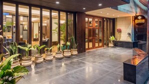 A hotel lobby with a reception desk, potted plants, and a large window. - Udaan Himalayan Suites and Spa (Darjeeling)